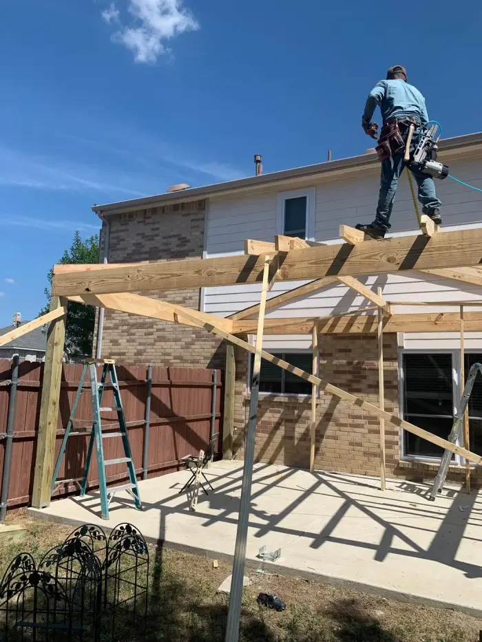 RGS General Contracting carpenter framing a patio cover structure over a new concrete slab in the Dallas-Fort Worth area